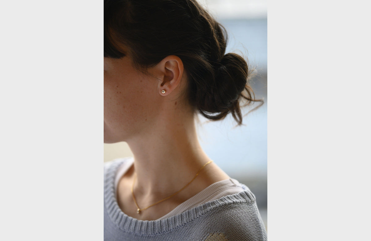 Woman Wearing Simple Gold and Diamond Stud Earrings